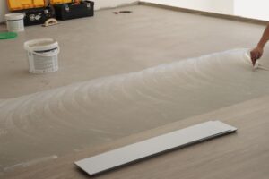 Aplicação de piso vinílico colado LVT com uso de adesivo sobre contrapiso nivelado em obra.