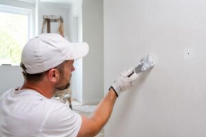 Aplicação de massa para drywall durante o reparo de uma pequena fissura na parede