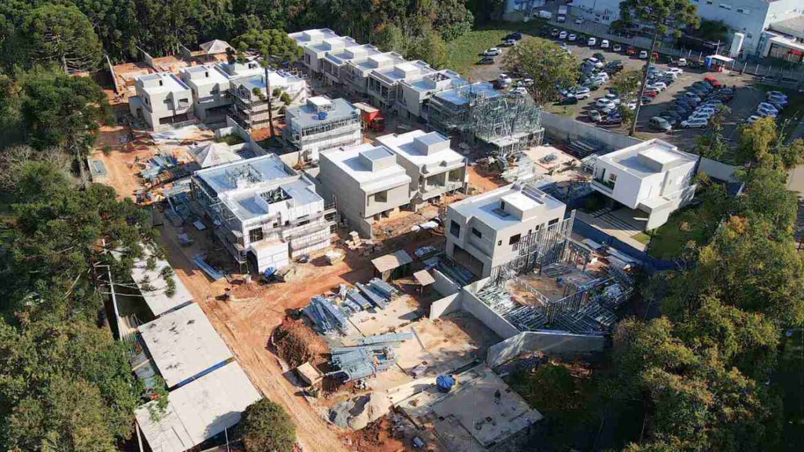 Condomínio residencial em Steel Frame com casas em diferentes etapas da construção, desde a estrutura até o acabamento.
