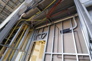 Instalação de tubulações hidráulicas, conduítes e caixas elétricas em paredes de Steel Frame antes do fechamento interno.