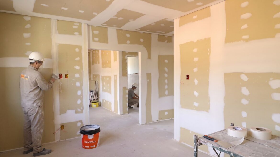 Profissional realizando o tratamento de juntas em uma parede de drywall